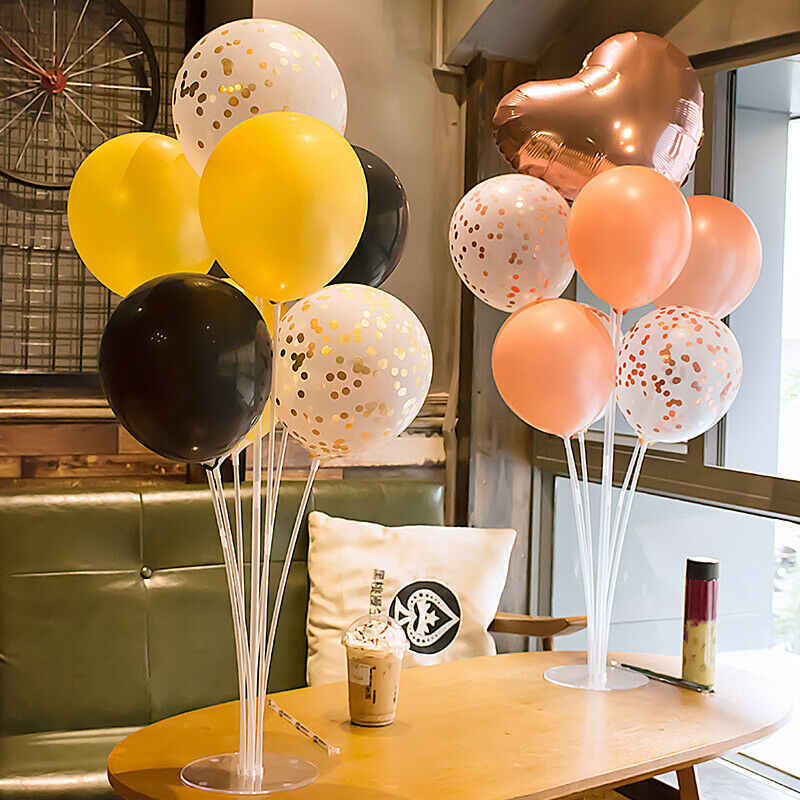 Two balloon stand kits with seven balloons each in different colors on a table in a coffee shop.