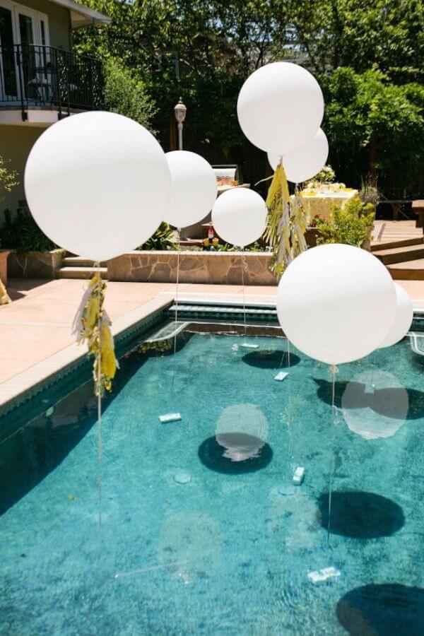 large white helium balloons floating over pool