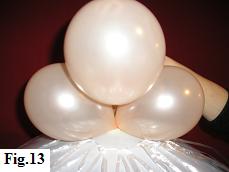 Pushing the second balloon duplet in place to create a 4 balloon cluster on top of the large balloon.