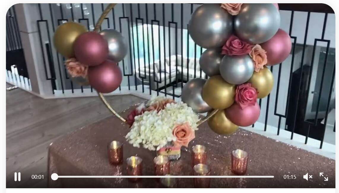 Balloon centerpiece with small latex balloons in chrome colors attached to a golden hula hoop ring, using a flower filled vase as base.