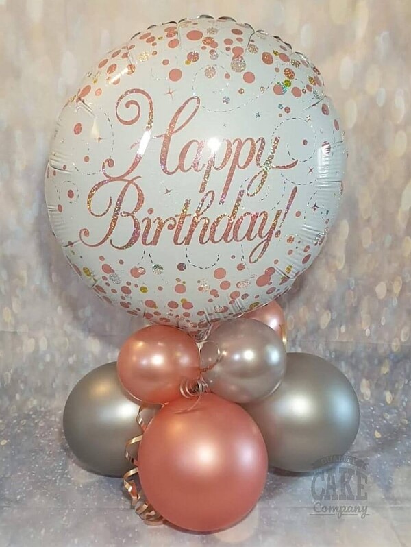 Air-filled balloon centerpiece made of two balloon quads as bas and a "Happy Birthday" foil balloon on top.