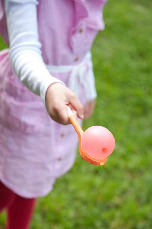 Girl balances water balloon on a spoon