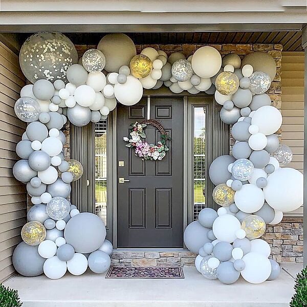 Organic balloon garland made of white, grey and confetti balloons framing a house entrance.