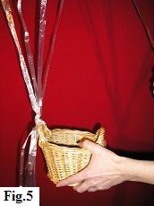 Attaching a wicker basket to one side of the hot air balloon netting.