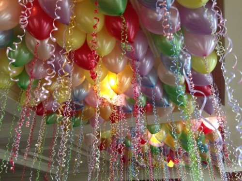 Ceiling decoration with colorful helium-filled latex balloons with ribbons.