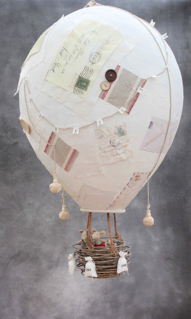 Large paper mache hot air balloon, decorated with vintage envelops and scraps of fabric, and toy mice as the passengers in the wicker basket.