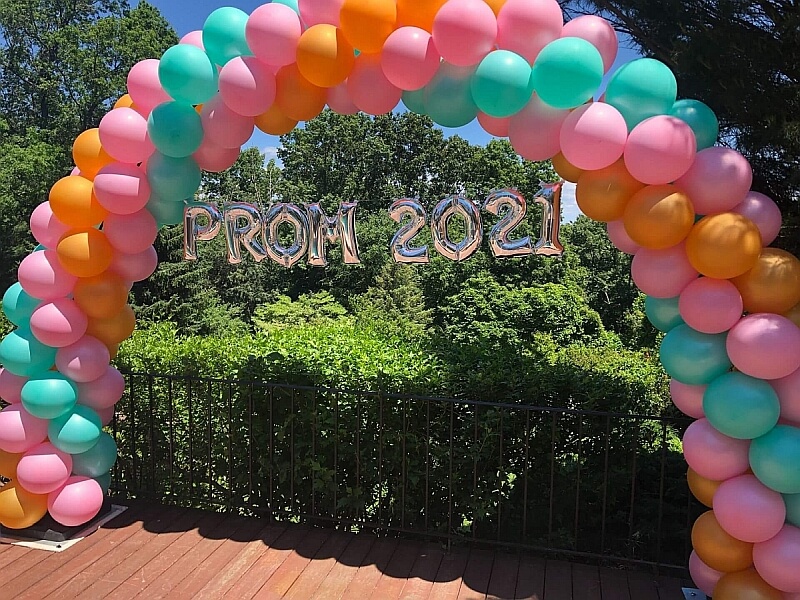 Outdoor balloon arch with spiral pattern in three colors.