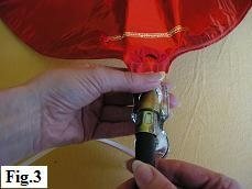 Inserting helium tank nozzle into mylar balloon valve.