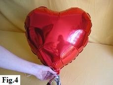 Inflating mylar balloon heart with helium.